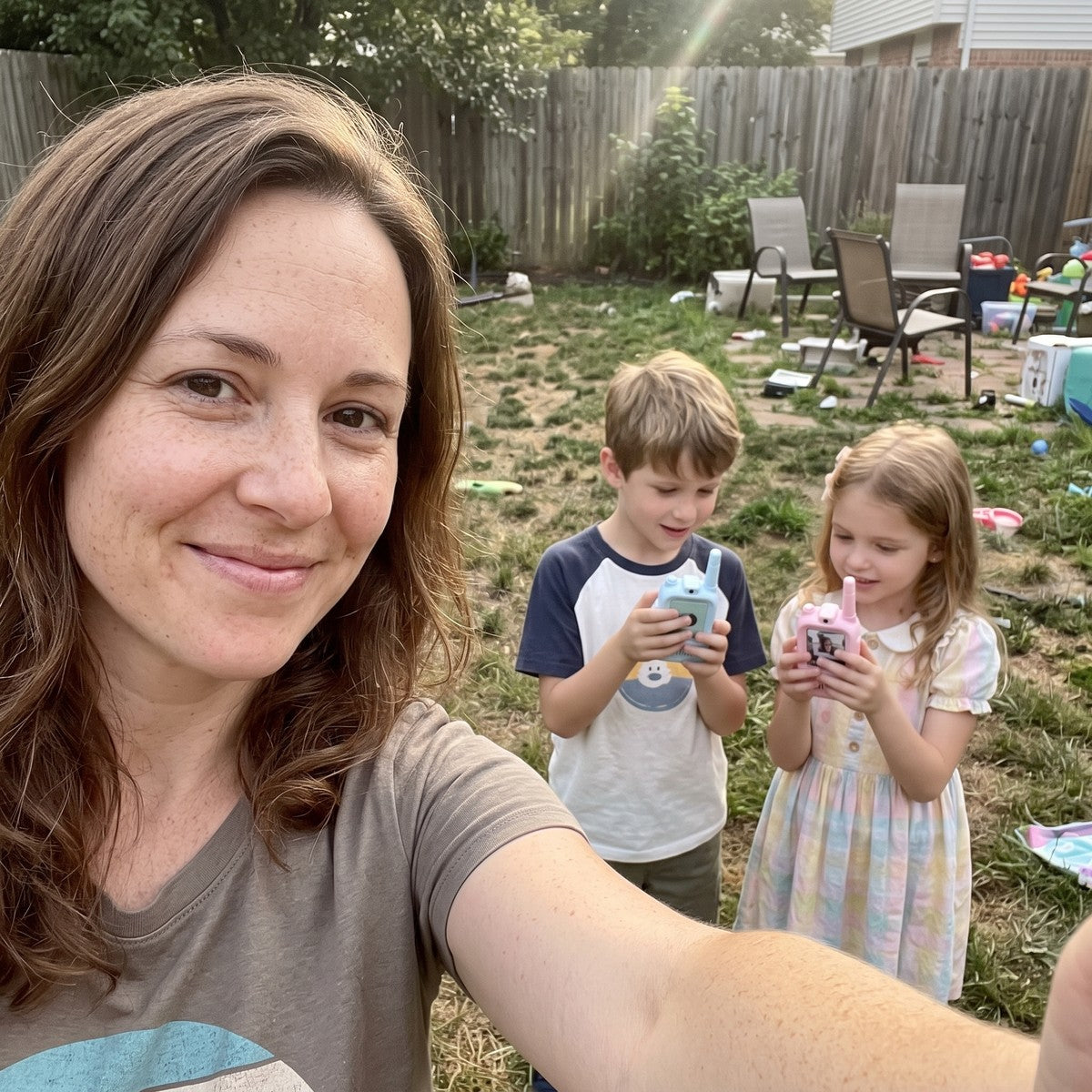 Mum taking a backyard selfie beside children using a blue and pink Playpal pair